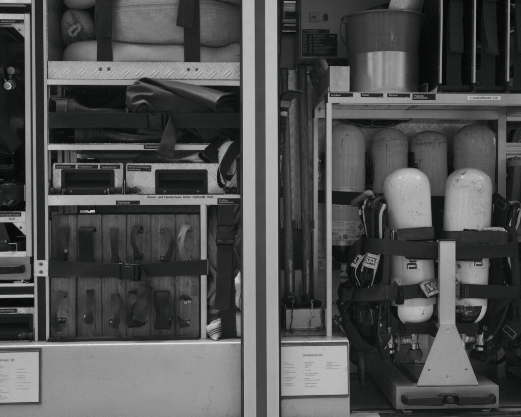Black and white photo of firetruck equipment and rescue gear neatly organized in compartments.