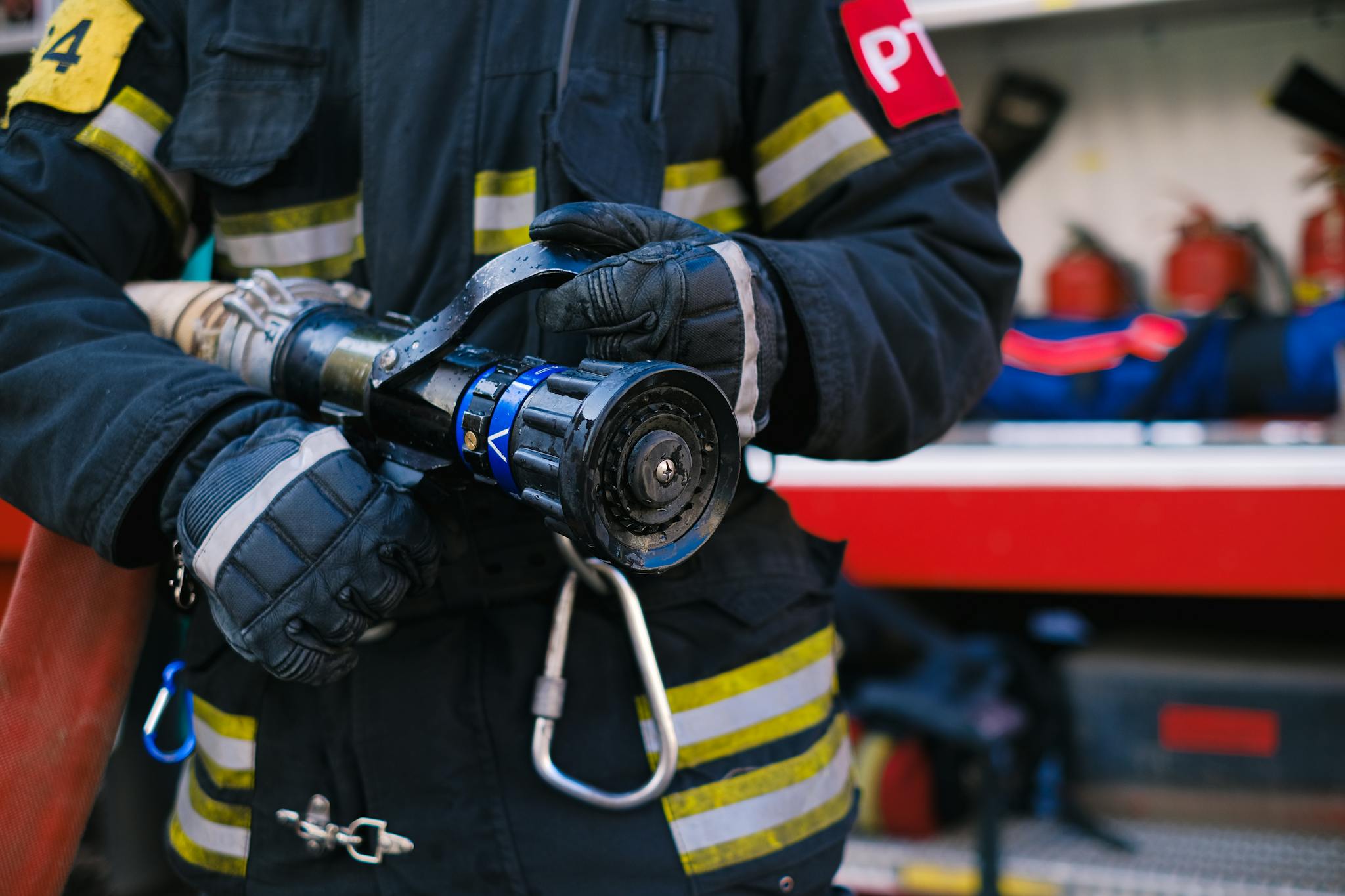 Close-up of firefighter holding a hose nozzle in safety uniform.